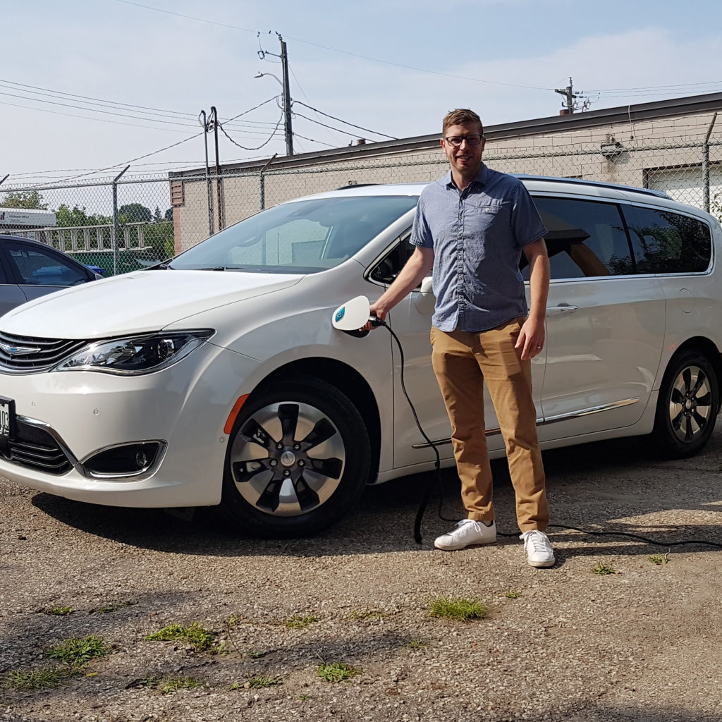 AET employee with electric vehicle being charged at the head office in Kitchener.