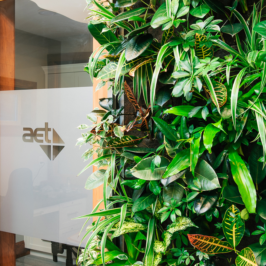 Living wall beside glass door with AET logo.