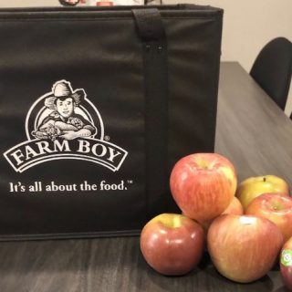 Apples sitting on a table beside a reusable grocery bag. 