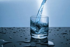 A clear glass with water being poured into it.